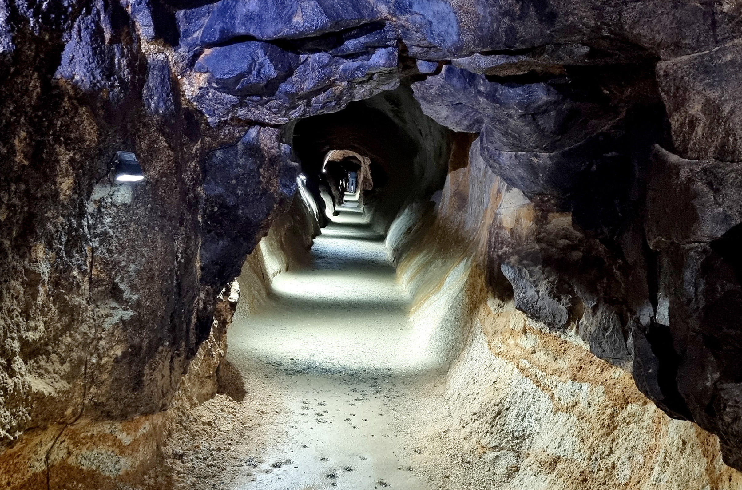 Beleuchteter Stollen mit schmalem Weg im Besucherbergwerk Gleißinger Fels.