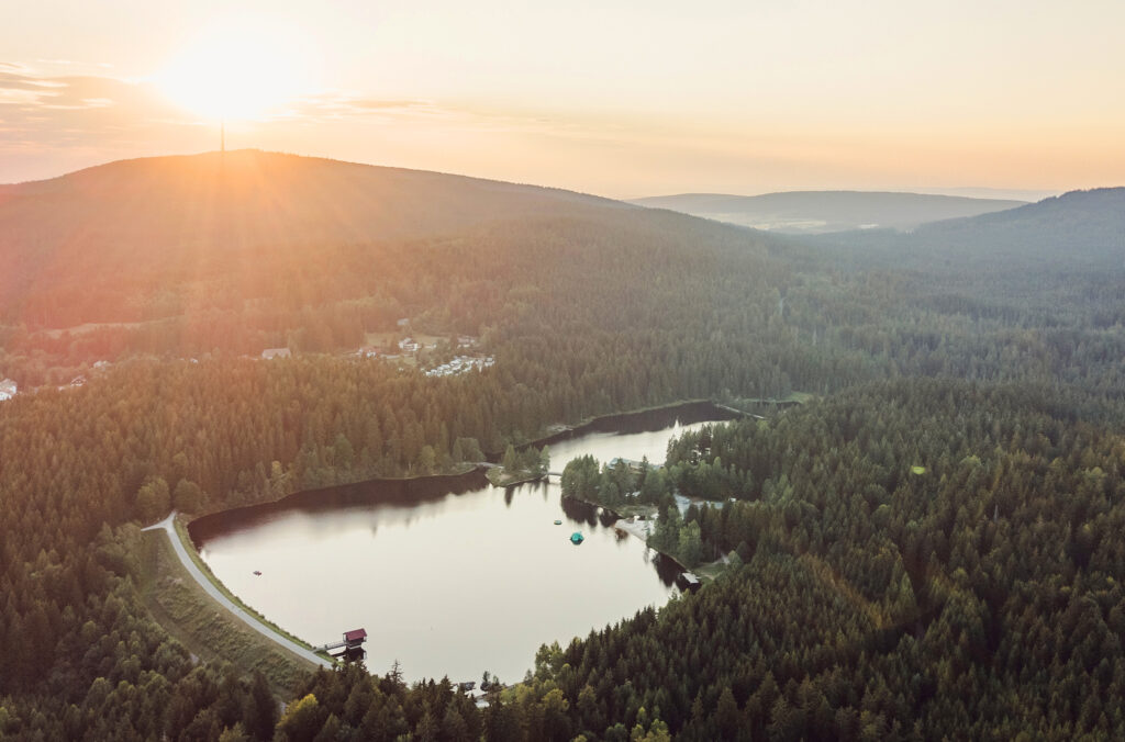 Der Fichtelsee liegt in der Erlebnisregion Ochsenkopf im Hohen Fichtelgebirge auf ca. 750 m NN unweit von der Ferienwohnung Siebenstern in Fichtelberg entfernt. Im Hintergrund wird der BErg Ochsenkopf von der Abendsonne angestraht.