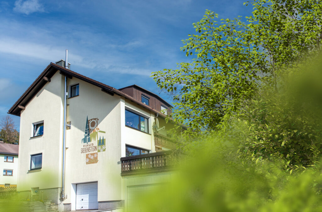 Außenansicht eines hellen Wohnhauses mit Balkon und Garage in ruhiger Wohnlage.